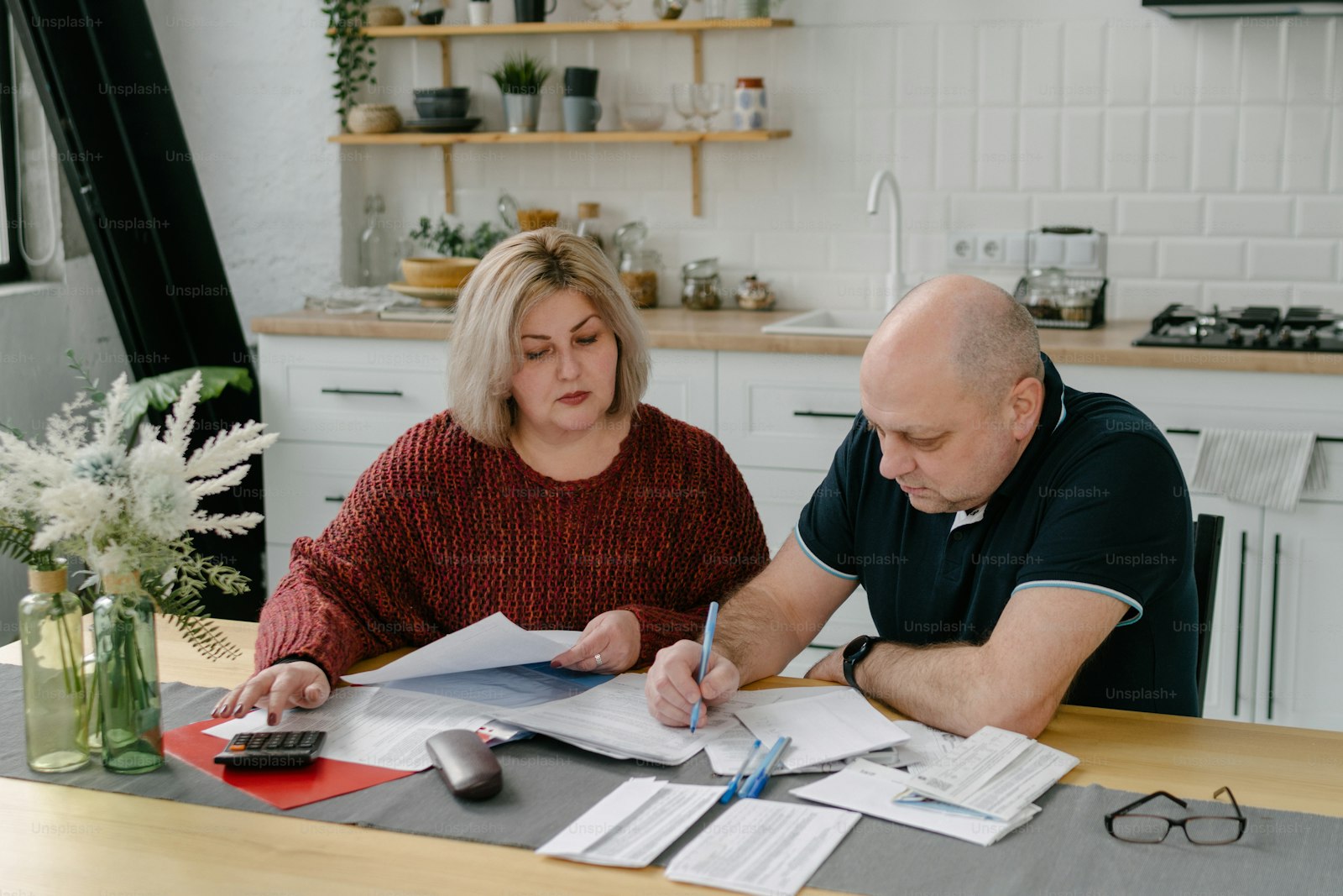 A couple comparing paperwork at a kitchen table